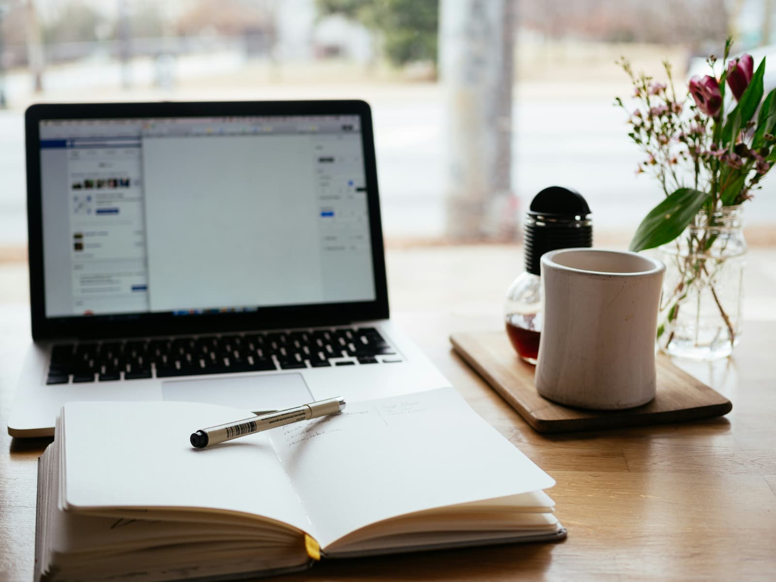 A laptop and open notebook on a desk by a window, the workspace of a team responding to updated digital skills standards