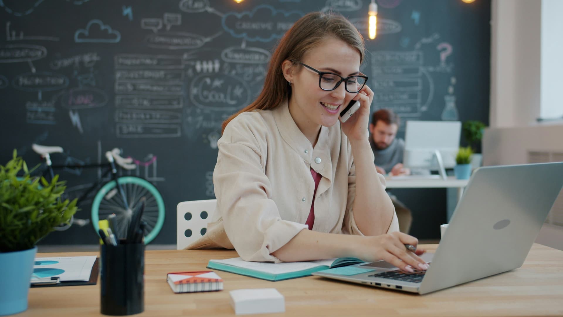 An employee using a laptop and phone together in a modern workplace